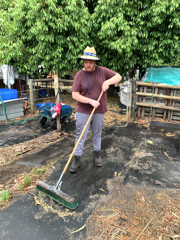 Cameron sweeping with a broom.