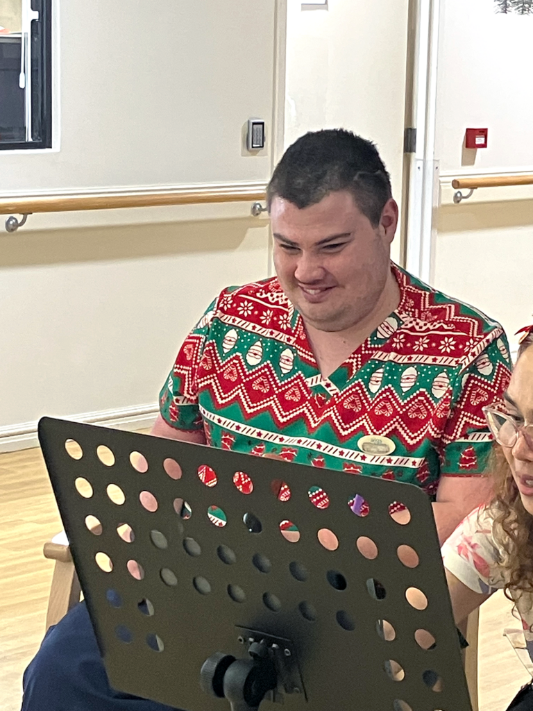 Jacob sitting down and smiling. He is dressed in a Christmas t-shirt.