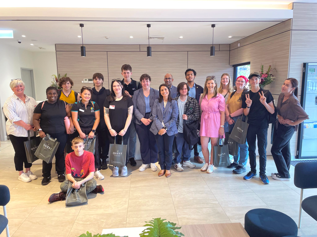 Large group of people standing alongside each other smiling for the camera in a reception area.