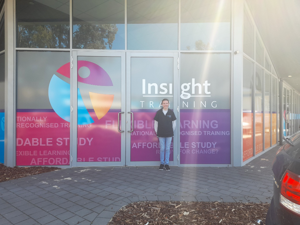 Zoe standing in front of the Insight building with customised signage on the glass windows.