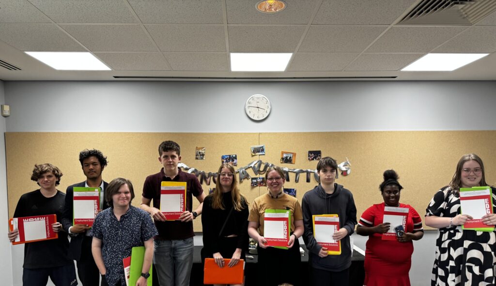 A group of students holding folders in a room.